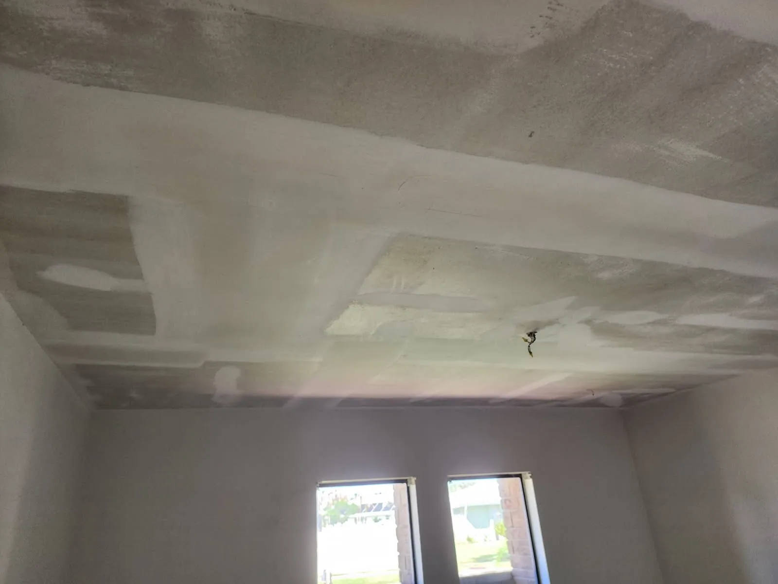 Bedroom ceiling with seams and patches coated in joint compound, ready for sanding